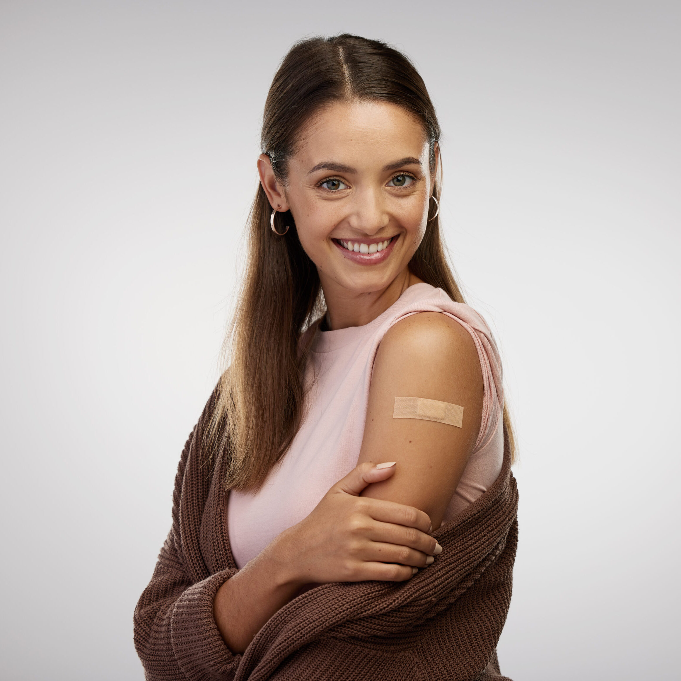 Shot of a young woman standing alone in the studio after getting vaccinated